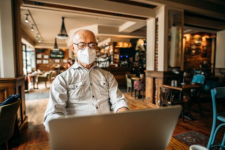 Hombre con máscara, trabajando en su computadora portátil