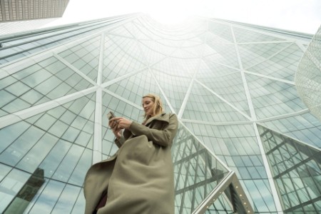 Femme utilisant son téléphone devant un building