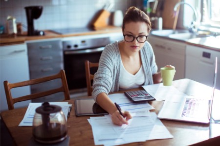 Jeune femme faisant ses factures dans sa cuisine