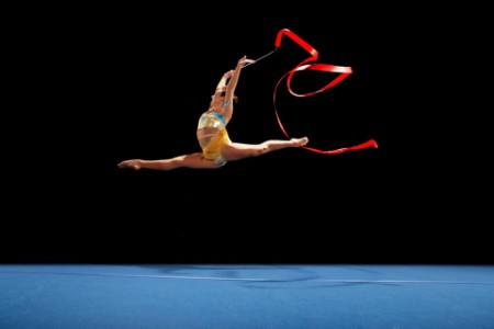 Athlète féminine effectuant un saut en l’air lors d’une performance de gymnastique rythmique