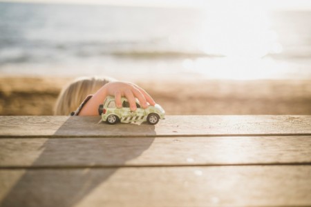 young child playing with car in a beach