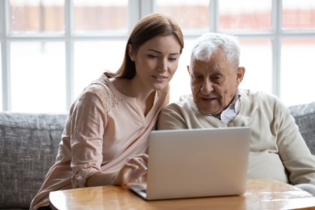 Une femme et une personne âgée consultent un ordinateur.