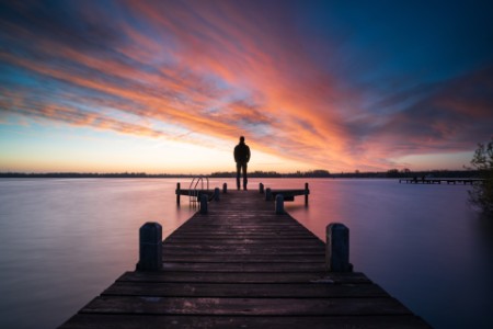 Un homme regardant un lac au coucher de soleil