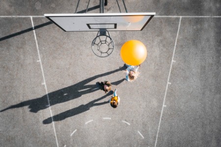 Image d'enfants jouant au basketball sur un terrain de basketball.