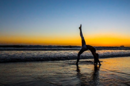 lány jógázik a tengerparton hajnalban