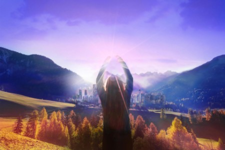 Woman reaches for the sun overlooking valley and mountains