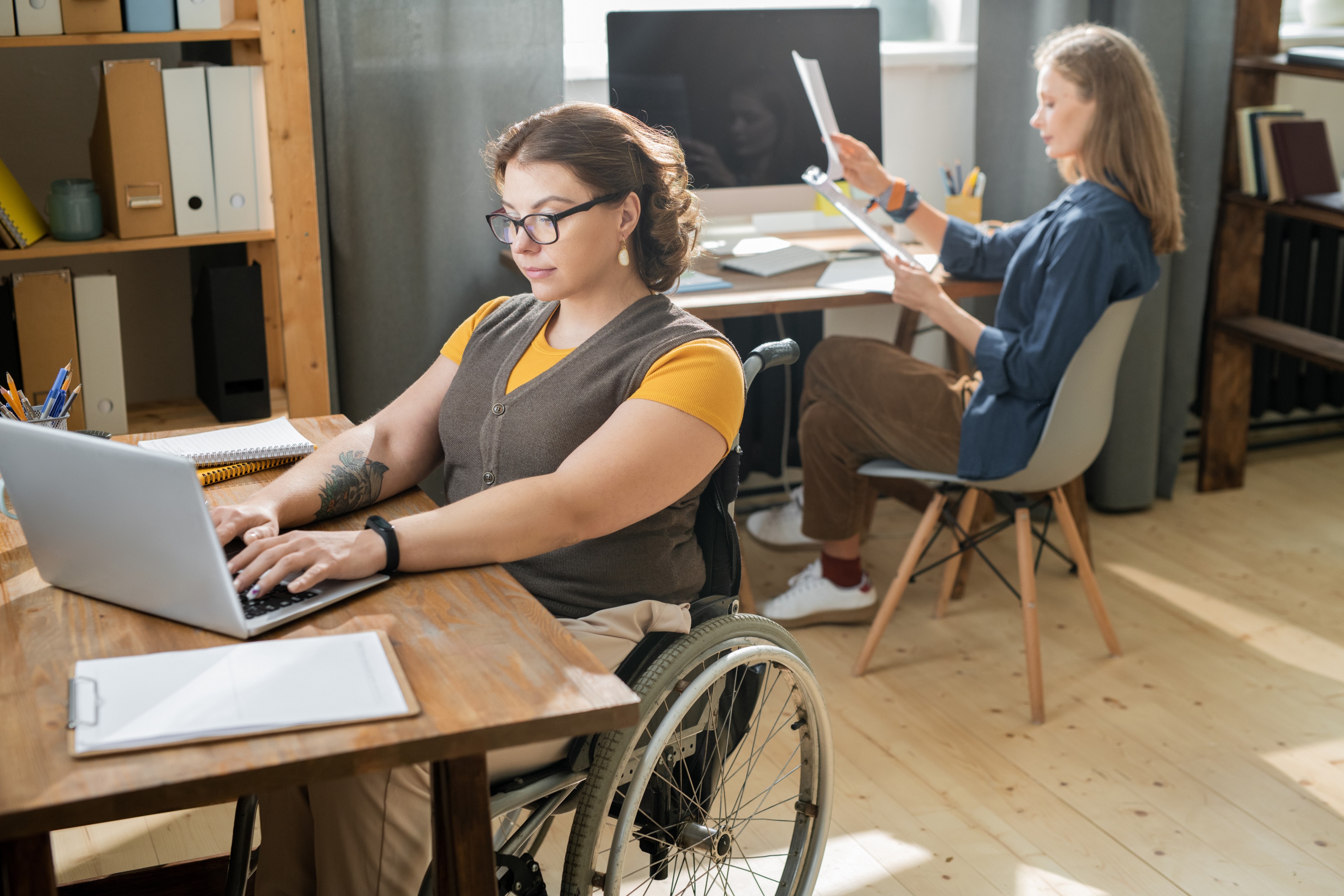 Young businesswoman sitting in wheelchair in front of laptop and networking