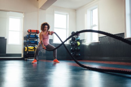 Vrouw traint met battle ropes in de sportschool