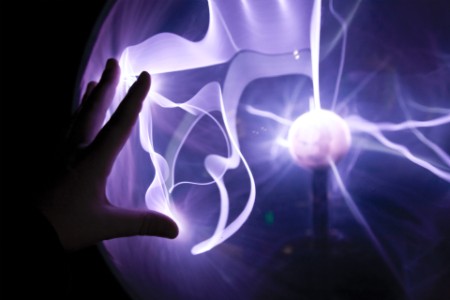 Closeup of a hand touching a plasma lamp.