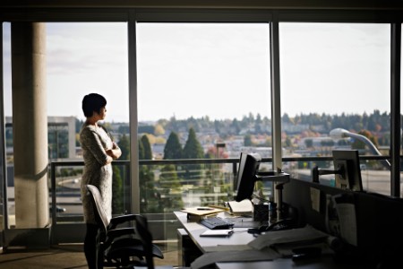En kvinne som står i et kontor, mens hun ser ut av vinduet. 
