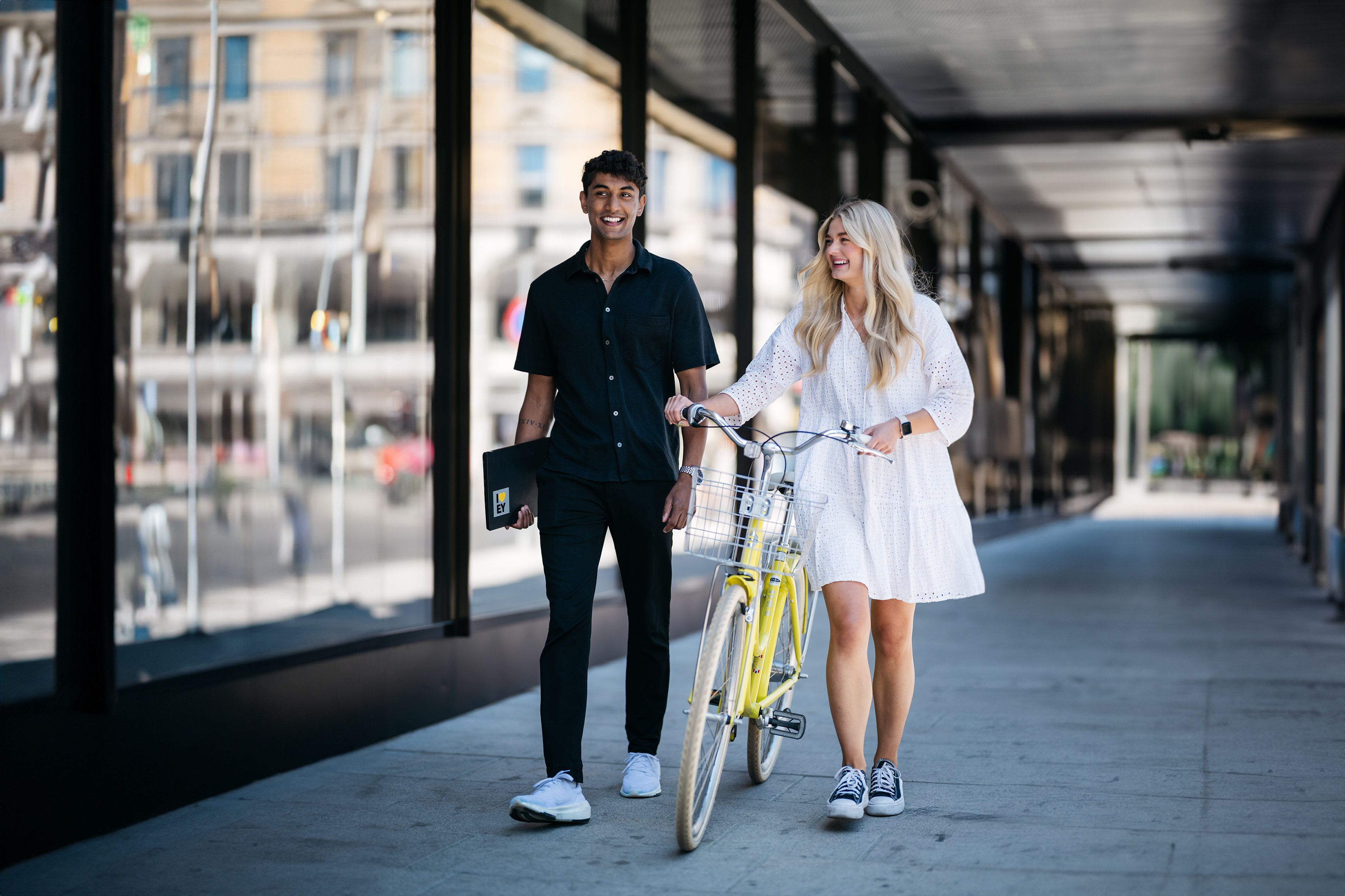 En mann og en kvinne går nedover veien med en gul sykkel.