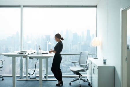 Forretningskvinne som jobber på datamaskinen på kontoret med vakker utsikt over skyline