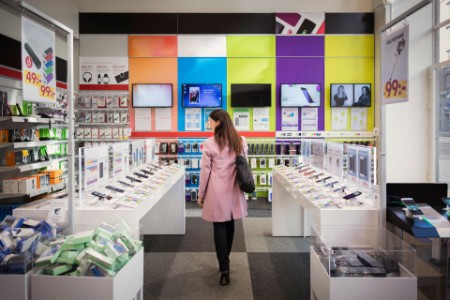 mulher branca dentro de uma loja avaliando os celulares à venda