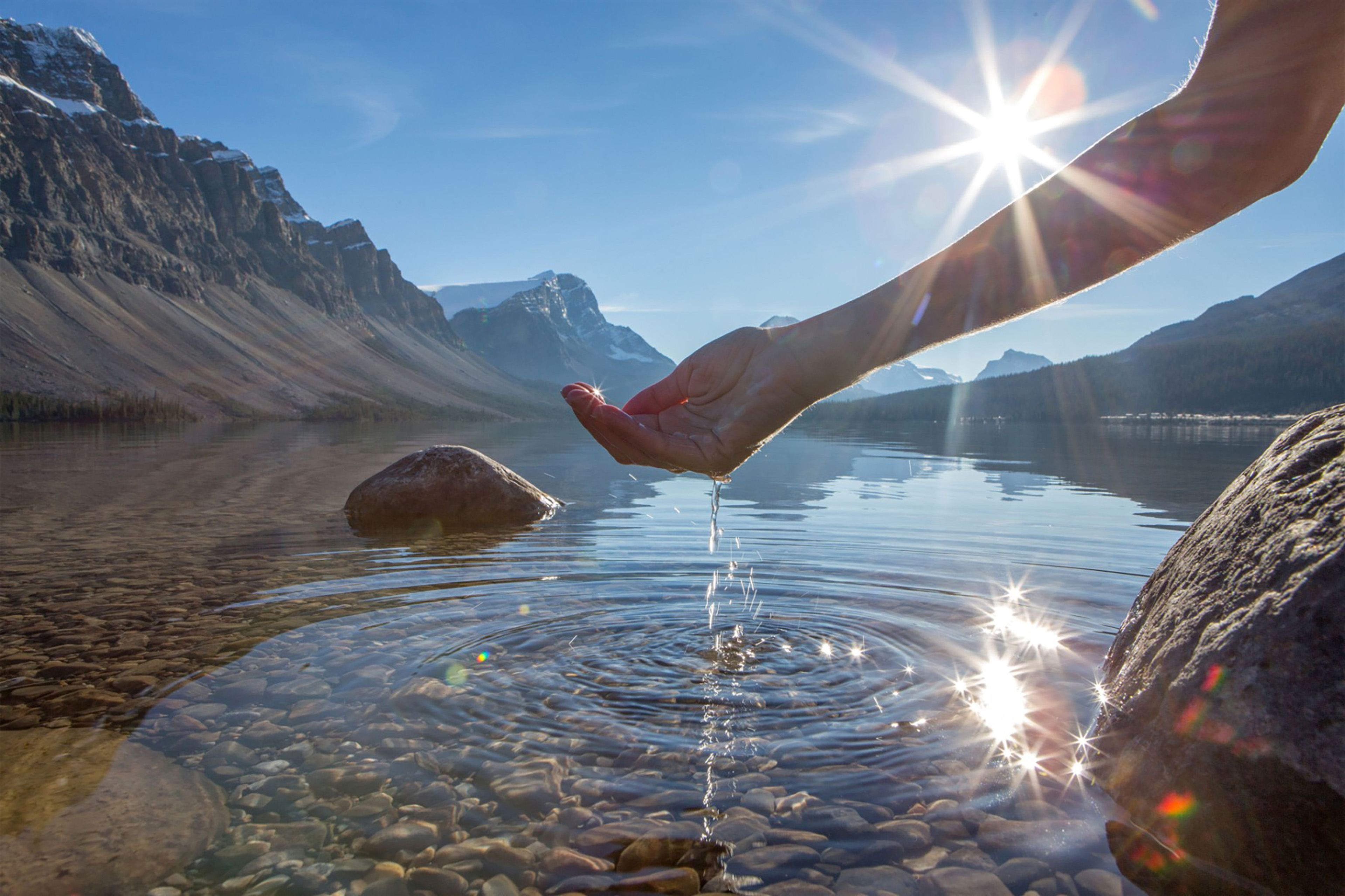 Human hand cupped to catch the fresh water from lake background