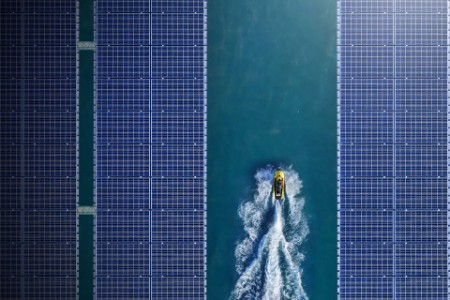 Aerial view of jetski between solar panels floating in a dam