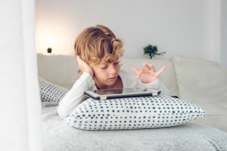 Boy browsing the iPad on the bed