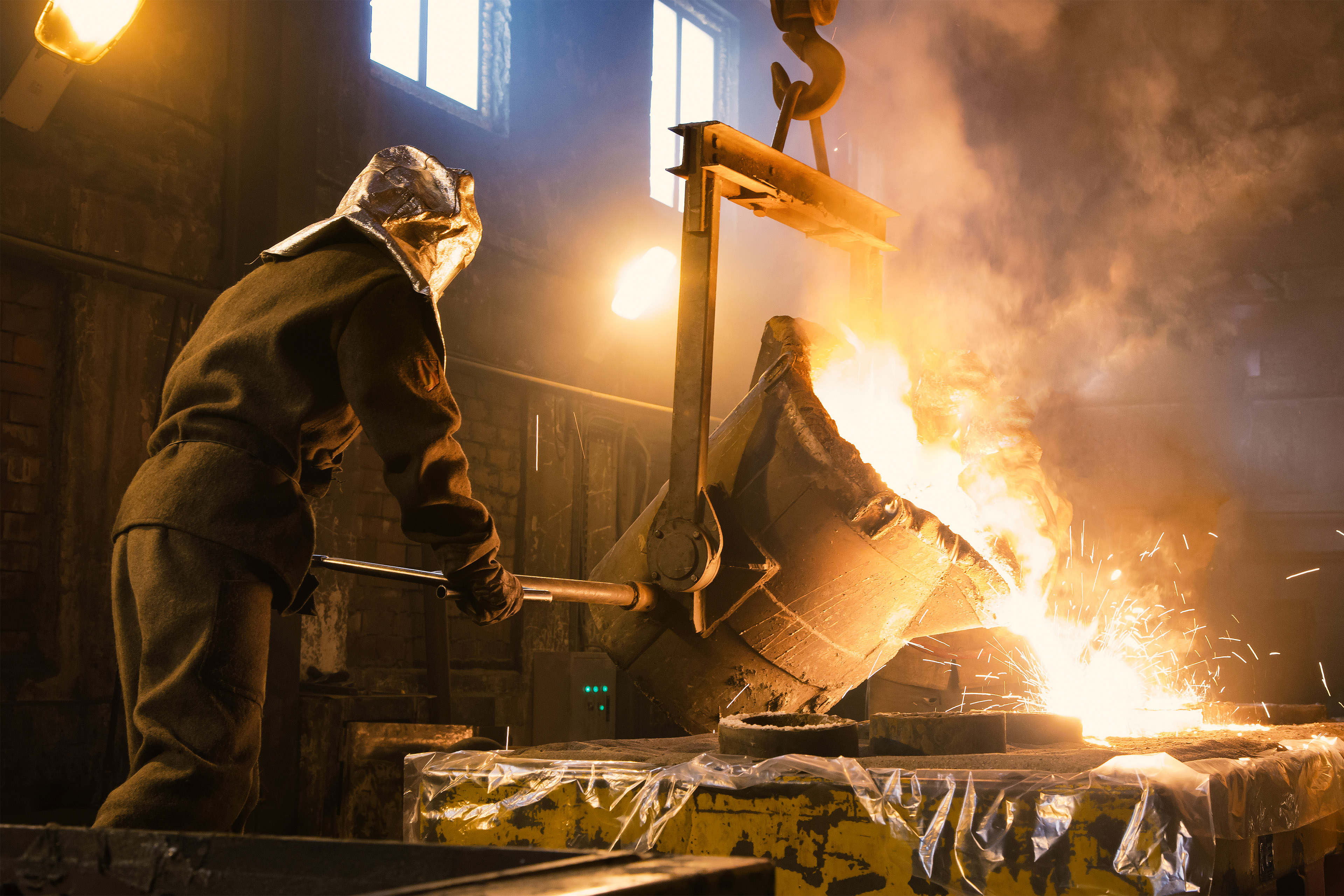 Worker controlling metal melting in furnaces. Workers operates at the metallurgical plant. The liquid metal is poured into molds.