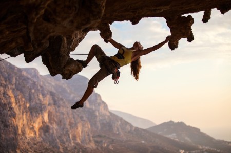 O femeie care escaladează liber un munte