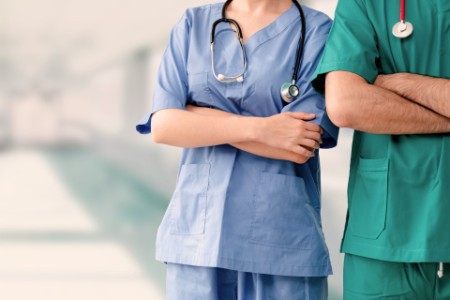 Läkare eller sjuksköterska som står med armarna i kors på sjukhuset