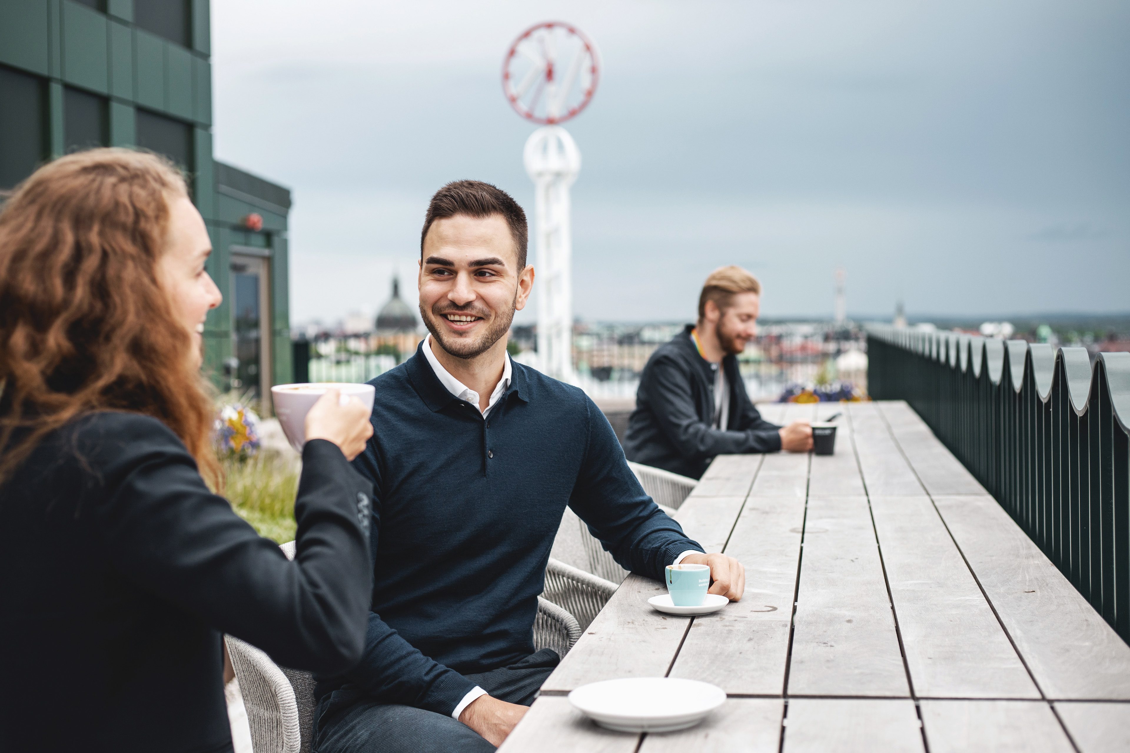  En kvinna och en man sitter på balkongen och tar en kaffepaus