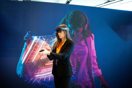 Kvinna använder VR-glasögon och står framför färgglad bakgrund