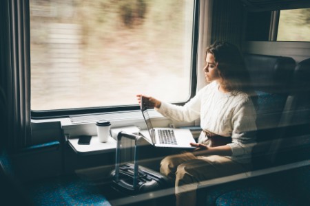 Bild på Kvinna arbetar på ett tåg med en bärbar dator.